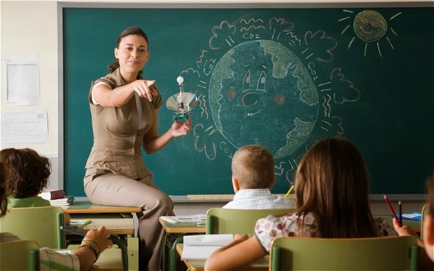 profesora con una pizarra al fondo en la que hay dibujado el planeta tierra